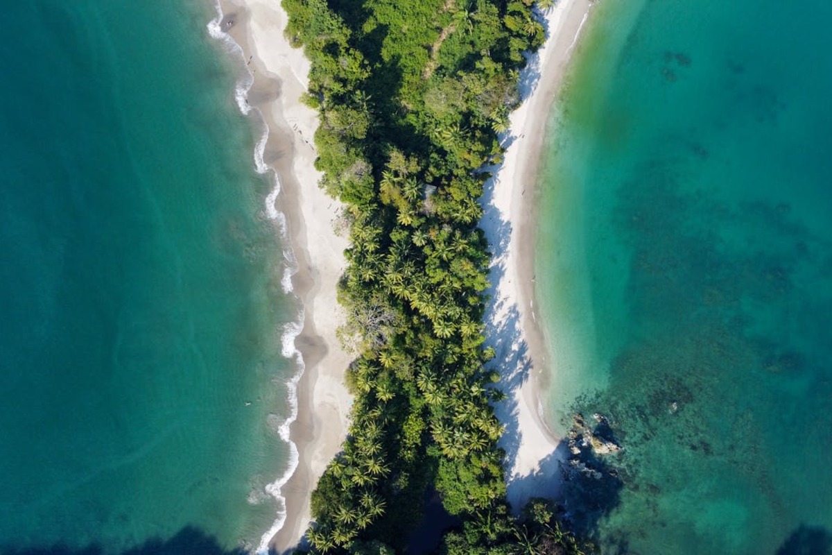 Manuel Antonio Beach Costa Rica aerial view showing lush tropical rainforest meeting turquoise Pacific Ocean
