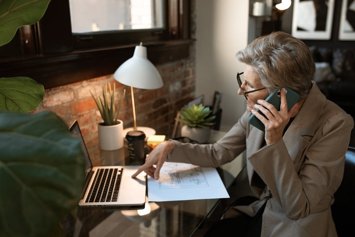 Businesswoman working on phone call while using laptop, representing AI voice agent client management