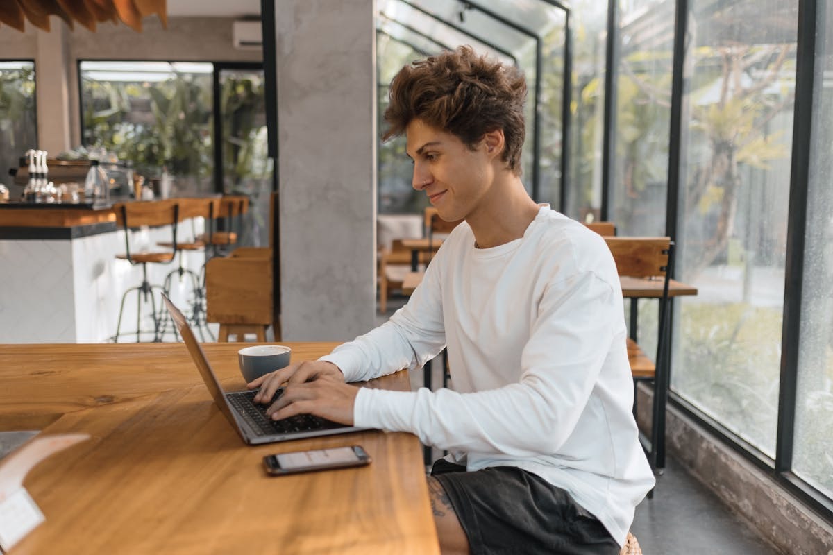 Young man working on a laptop in a cafe as a digital nomad AI consultant