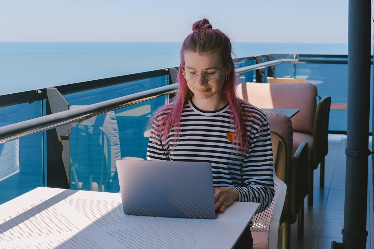 Digital nomad working on laptop with ocean view - remote work lifestyle abroad