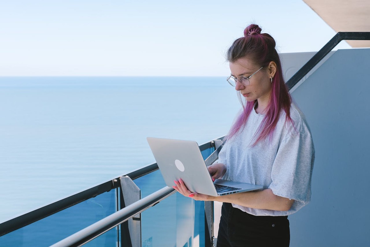 Digital nomad working on laptop by the sea, representing the expat remote work lifestyle and financial planning considerations