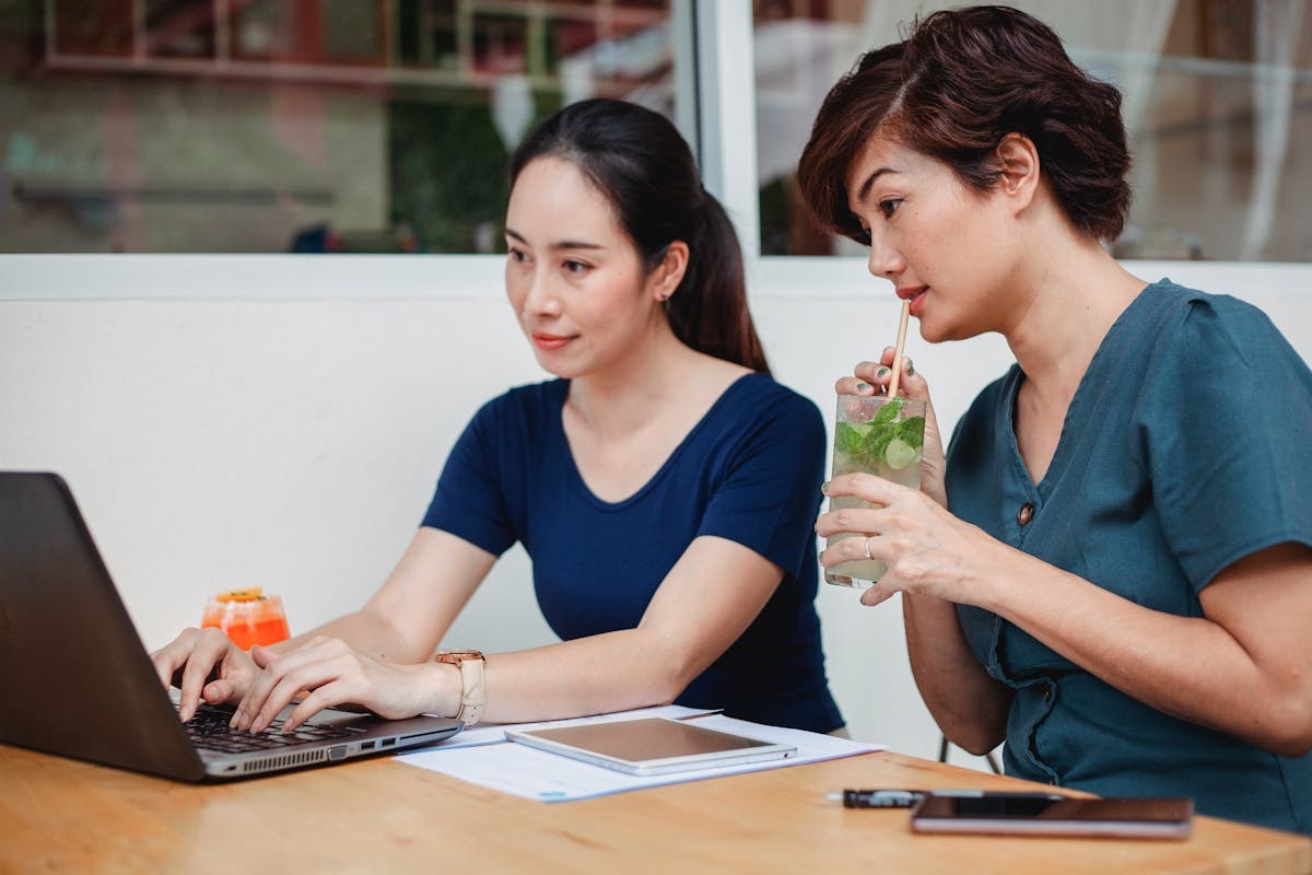 Two digital nomads working on laptops in a cafe managing their e-commerce store