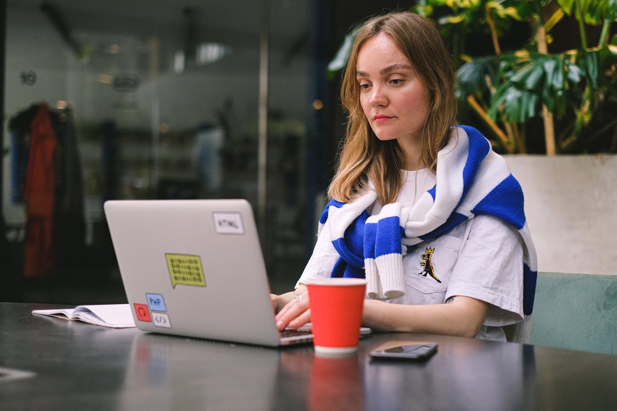 Freelancer working on laptop in cafe abroad navigating US self-employment tax obligations as digital nomad