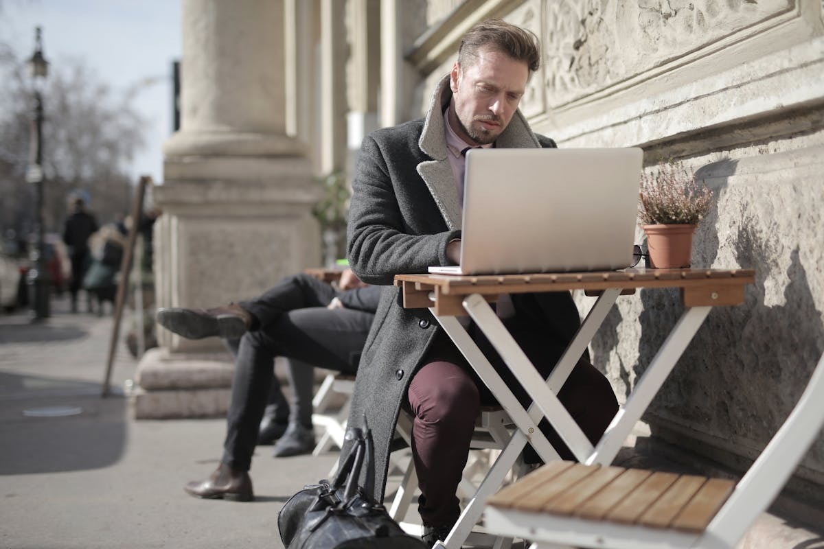Freelancer working on laptop at an outdoor cafe abroad, representing expat remote work and financial planning