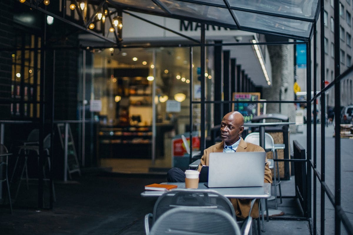 US expat working on laptop at an outdoor cafe abroad, representing foreign business ownership