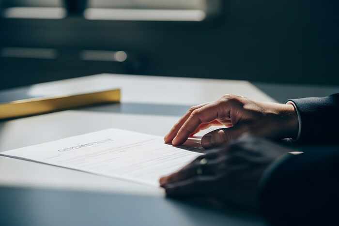 Close-up of hands reviewing IRA custodian documents on clean white desk in natural light