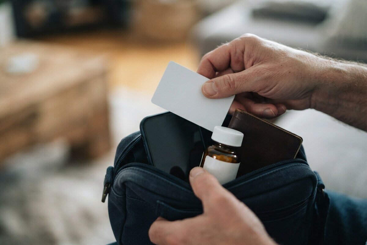 Hands packing insurance card and medicine into emergency pouch