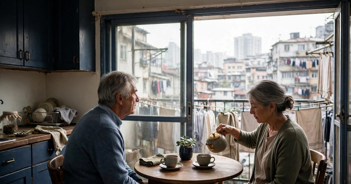 Older couple pouring tea at a round kitchen table in morning light