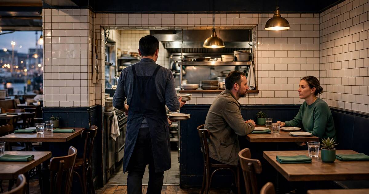 Host carrying plates through a small restaurant after the dinner rush