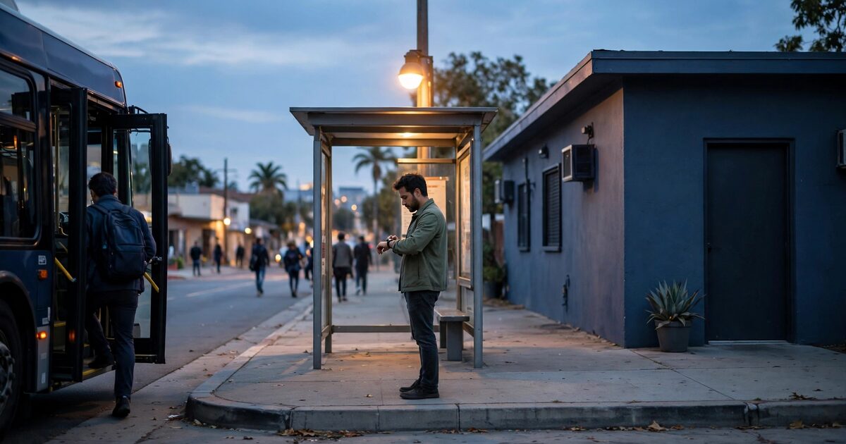 Person checking a watch at a dusk bus stop outside a low clinic