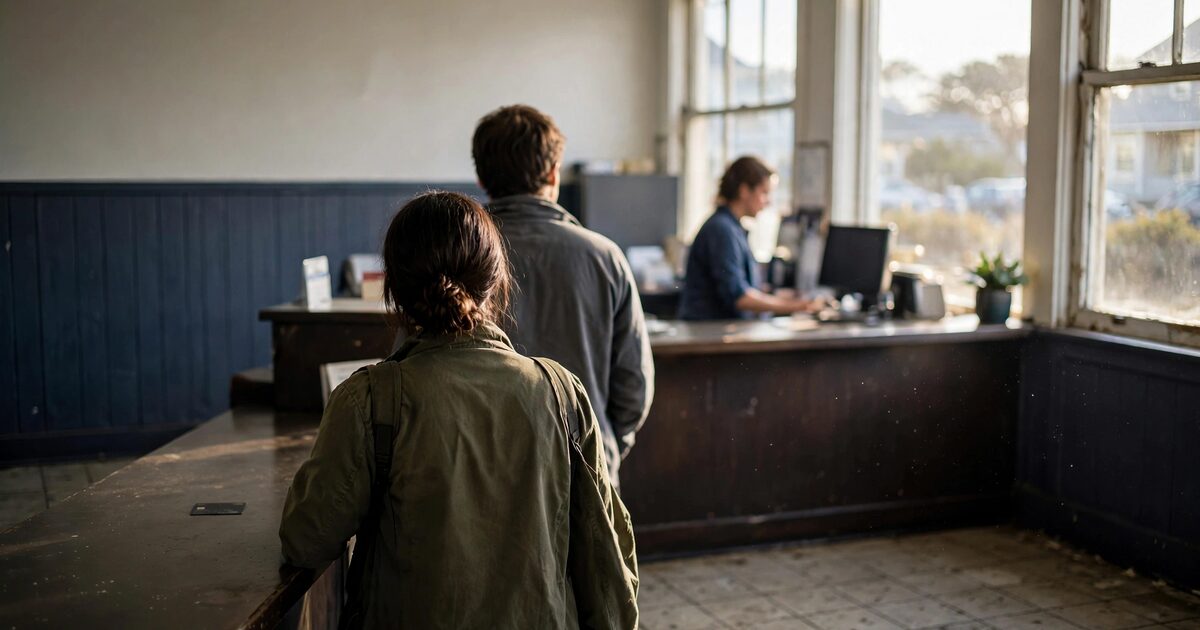 Two people from behind at a neighborhood bank counter in morning light