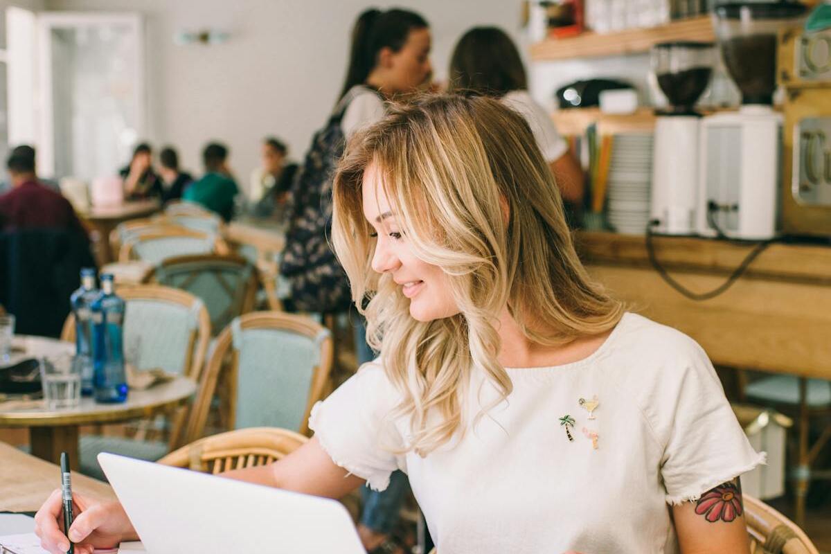 Digital nomad working on laptop in a coffee shop abroad — the AI video freelancing lifestyle